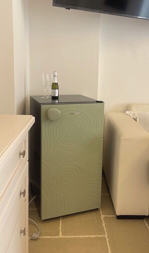 Ein kompakter Kühlschrank mit einem Rundmuster, eine Weinflasche und zwei Gläser darauf.