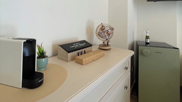 Een kitchenette met een koffieapparaat, een wereldbol, een fles wijn en een kleine plant.
