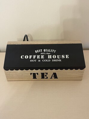 A wooden box with a black lid, labeled 'BEST QUALITY COFFEE HOUSE HOT & COLD DRINK' and 'TEA'.