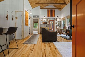A spacious room with a wooden floor, a sofa, a dining table with chairs, and a fireplace.