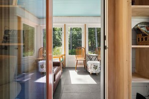 A room with a sliding glass door leading to a balcony with two wooden chairs and a table.