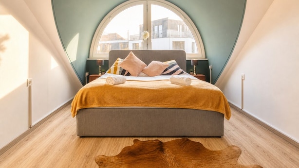 A bedroom with a large bed, a window, and a wooden floor.