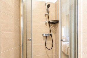 A shower with a handheld showerhead and a handheld scrubber.