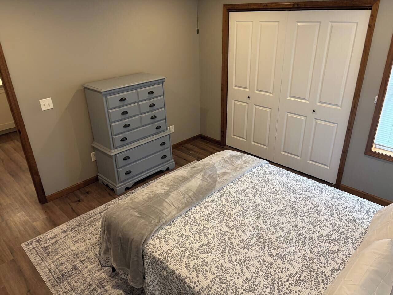 A bedroom with a bed, a dresser, and a closet.