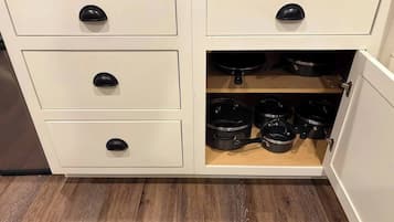 Una cocina con tres cajones y un armario que contiene ollas y sartenes.