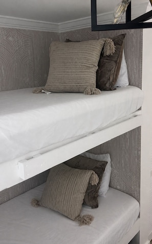Uma cama box com dois beliches, cada um com travesseiro e cobertor.