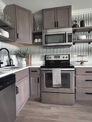 Uma cozinha equipada com micro-ondas, forno e máquina de lavar loiça embutidos.