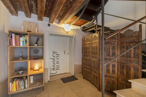 A laundry room with a wooden door, a bookshelf with books and decorative items, and a staircase with intricate woodwork. - Central Modern Loft | Rooftop Patio, Full Kitchen | Great Views (Venezia)