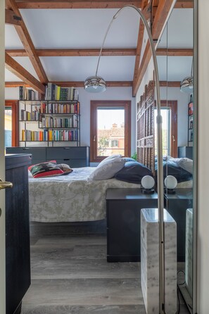 Une chambre à coucher avec un lit, des tables de chevet, une bibliothèque et une fenêtre.