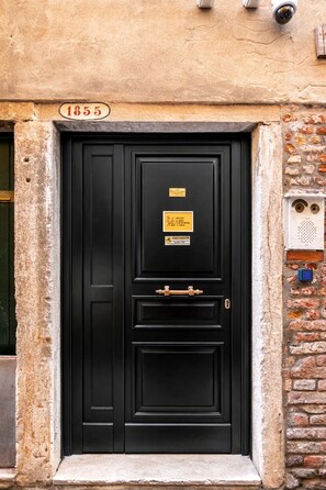 Une porte noire avec une poignée en laiton, une plaque et le numéro « 1855 » au-dessus.