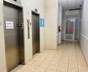 A corridor with two freight elevators, a fire extinguisher, and a door with a pink sign. - Seaside Escape at Luquillo Beach (Luquillo)