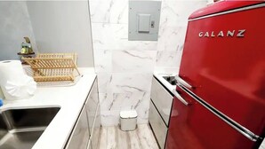 A compact kitchen with a red Galanz refrigerator, a sink, and a marble backsplash. - Seaside Escape at Luquillo Beach (Luquillo)
