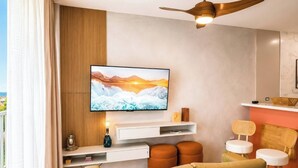 A modern living room with a flat-screen TV mounted on the wall, a ceiling fan, and a sofa. - Seaside Escape at Luquillo Beach (Luquillo)