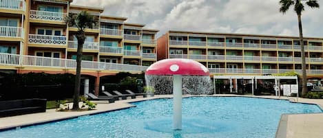 Une piscine agrémentée d’une fontaine, entourée d’immeubles à plusieurs étages dotés de balcons.