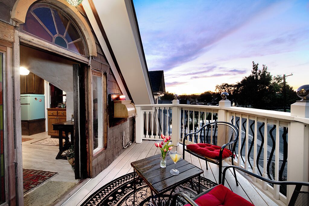 A balcony with a table, chairs, and a view of the sky.