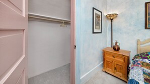 A bedroom with a wooden dresser, a hanging light fixture, and a bed with a colorful quilt.