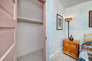 A bedroom with a wooden dresser, a hanging light fixture, and a bed with a colorful quilt.