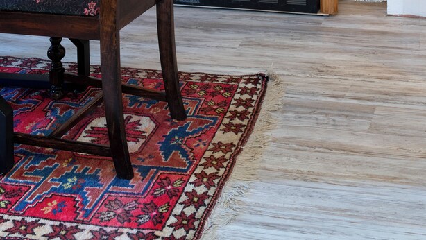 A room with a fireplace, a wooden chair, a table, and a patterned rug.