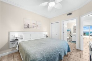 A bedroom with a bed, bedside tables, a ceiling fan, and artwork on the wall.