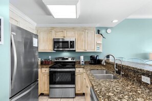 A modern kitchen with stainless steel appliances, granite countertops, and light wood cabinetry. - Panama City Beach Oasis: Panoramic Gulf Views & Direct Beach Access (Panama City Beach)