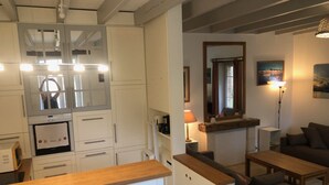 Un espai habitable compacte amb una cuineta, una zona de menjador i una zona de seients amb un sofà i una taula.