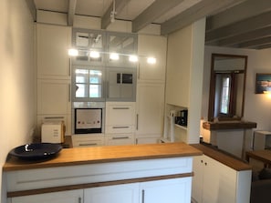 A modern kitchen with white cabinetry, a wooden countertop, and built-in appliances. - The Saddlery (Chaumes-en-Retz)