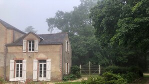 Una casa de dues plantes amb un camí de grava i una porta de fusta.