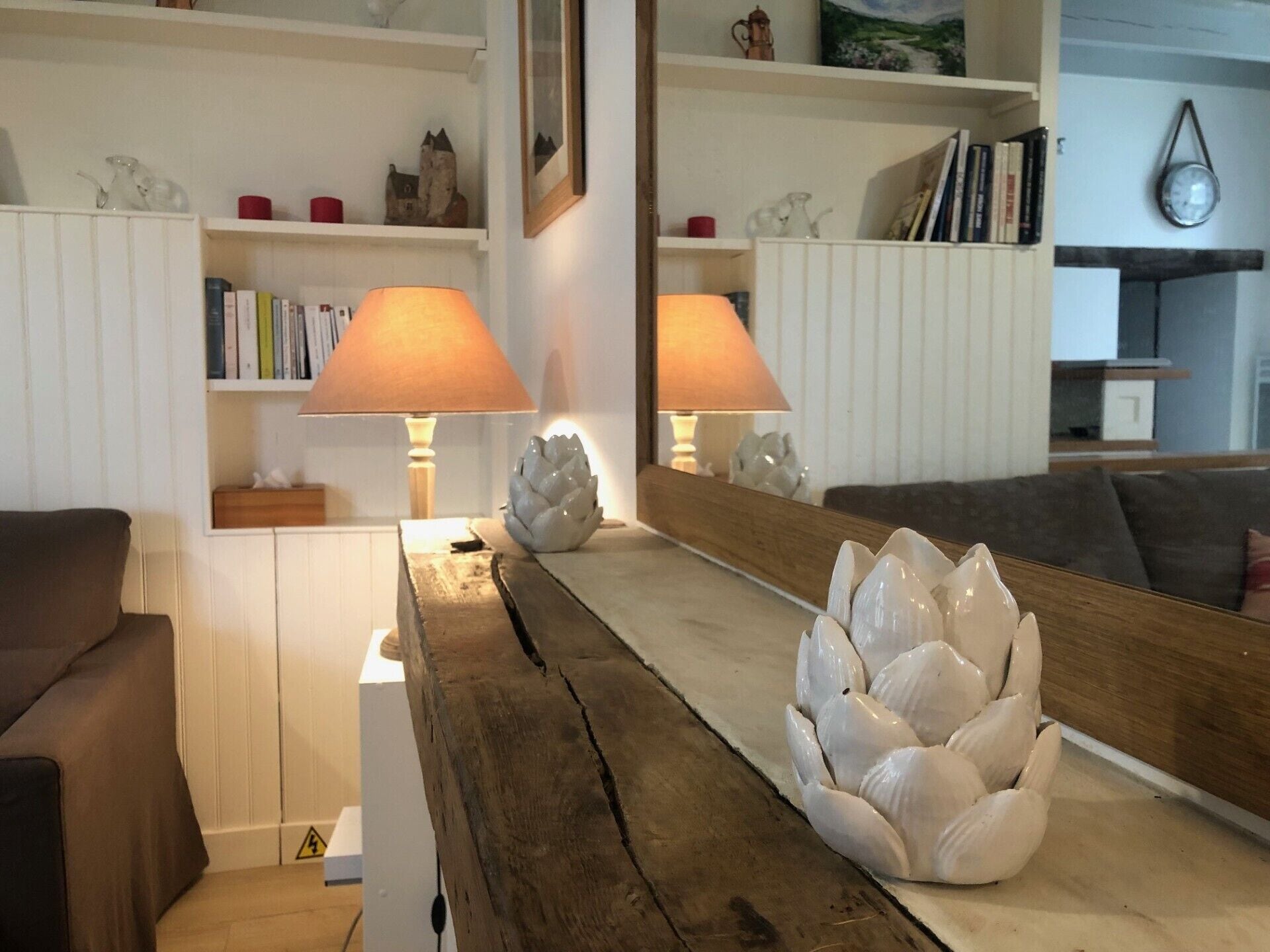 A living room with a wooden coffee table, two lamps, a sofa, and a bookshelf with various items.