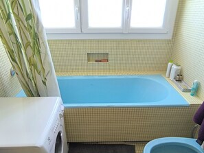 Ein Badezimmer mit einer blauen Badewanne, einer Waschmaschine und einer Toilette.