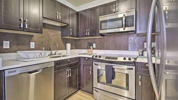 A modern kitchen with stainless steel appliances, dark wood cabinets, and a granite countertop.