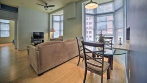 A living room with a sofa, a TV, and a dining area with a glass table and chairs.