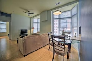 A living room with a sofa, a TV, and a dining area with a glass table and chairs.