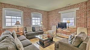 A living room with brick walls, a sofa set, a coffee table, and a television. - Convention center Indoor free parking (Baltimore)