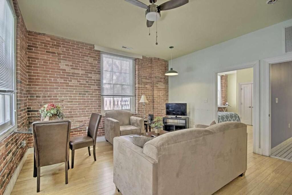 A living room with a brick wall, a ceiling fan, a TV, and a sofa.