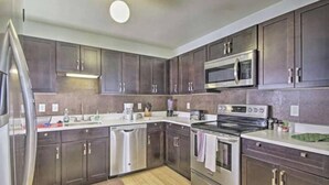 A modern kitchen with dark cabinets, stainless steel appliances, and a central island.
