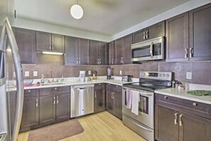 A modern kitchen with dark cabinets, stainless steel appliances, and a central island.