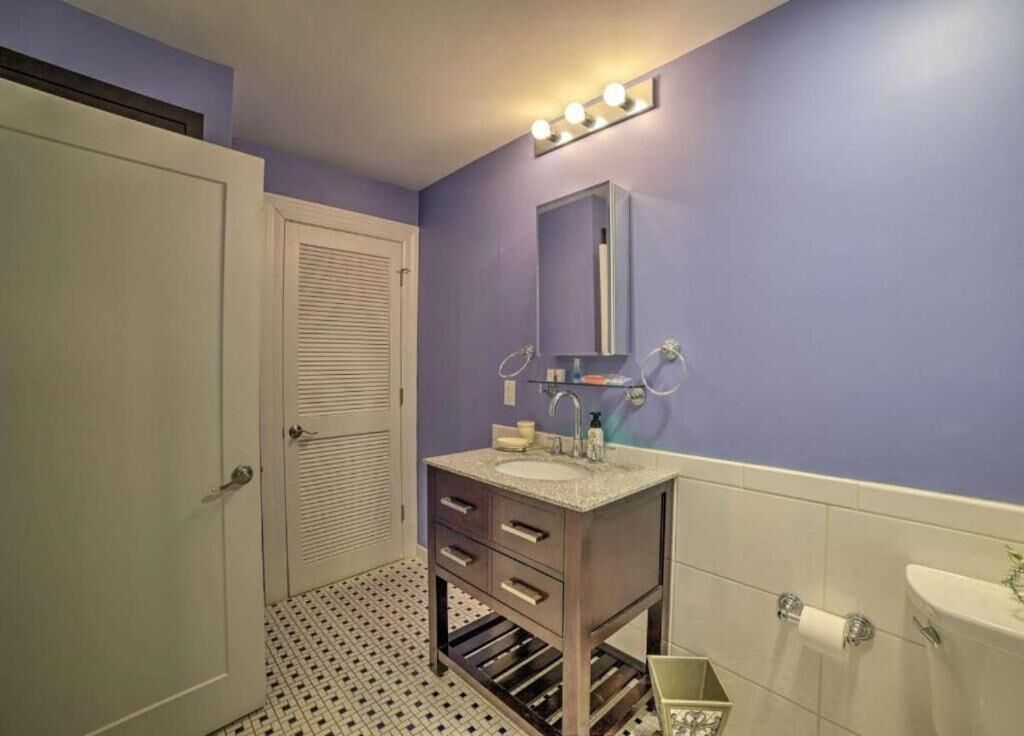 A bathroom with a vanity, sink, mirror, and towel rack.