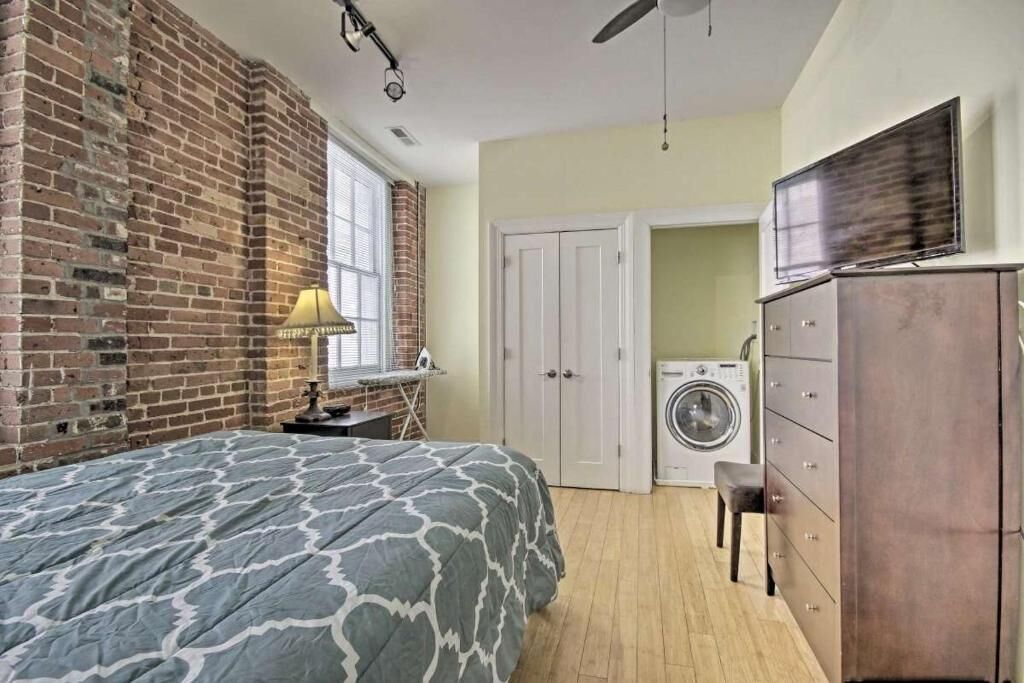 Een slaapkamer met een bed, een wasmachine en een dressoir.