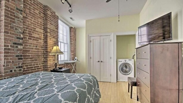 A bedroom with a bed, a washing machine, and a dresser. - Convention center Indoor free parking (Baltimore)