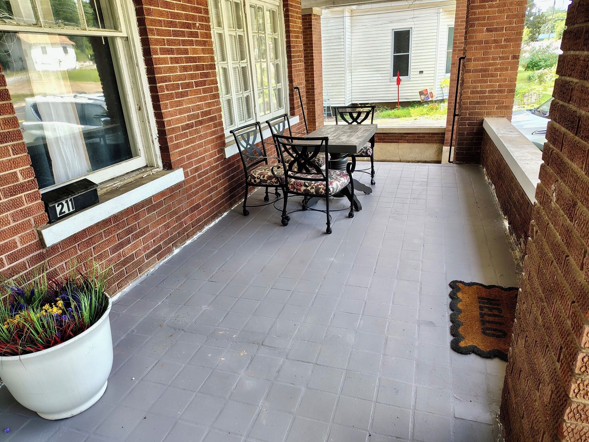 A brick patio with a table and chairs, a potted plant, and a mailbox.
