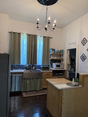 Una cocina equipada con refrigerador, microondas y pileta. Hay una araña colgando del techo.