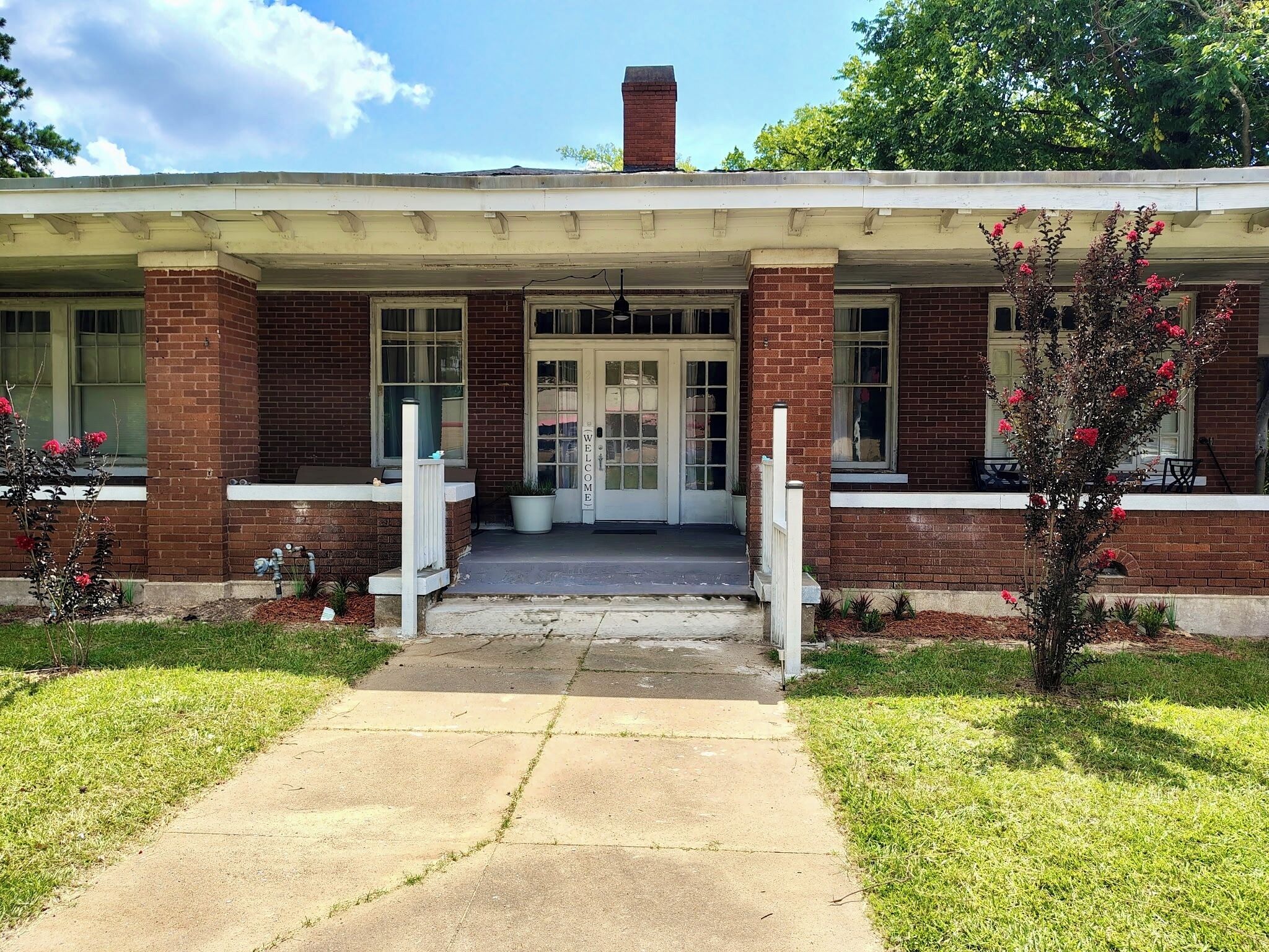 A two-story building with a brick facade, a front porch, and a welcoming sign.