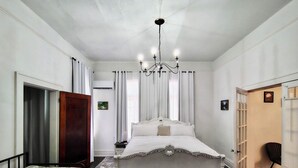 A bedroom with a large bed, a smaller bed, a chandelier, and a door leading to another room.