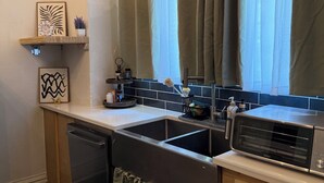 A kitchen with a dishwasher, a toaster oven, and a window with curtains.