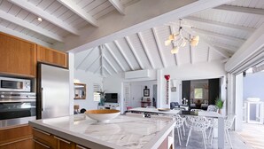 A modern kitchen with a marble countertop, wooden cabinets, and a built-in oven. - Villa Panorama Marin · Bois Jolan · 5 BR · 426969 (Sainte-Anne)