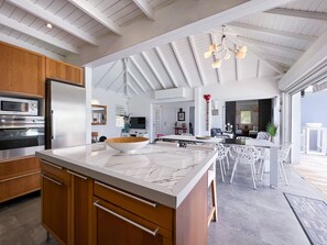 A modern kitchen with a marble countertop, wooden cabinets, and a built-in oven. - Villa Panorama Marin · Bois Jolan · 5 BR · 426969 (Sainte-Anne)