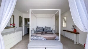 A bedroom with a canopy bed, bedside tables, a dresser, and a mirror. - Villa Panorama Marin · Bois Jolan · 5 BR · 426969 (Sainte-Anne)