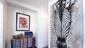 A hallway with a colorful striped cabinet, a framed abstract painting, and a large zebra mural. - Villa Panorama Marin · Bois Jolan · 5 BR · 426969 (Sainte-Anne)