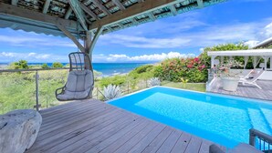 A wooden deck with a pool, a hanging chair, and a view of the ocean. - Villa Panorama Marin · Bois Jolan · 5 BR · 426969 (Sainte-Anne)