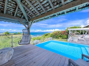 A wooden deck with a pool, a hanging chair, and a view of the ocean. - Villa Panorama Marin · Bois Jolan · 5 BR · 426969 (Sainte-Anne)